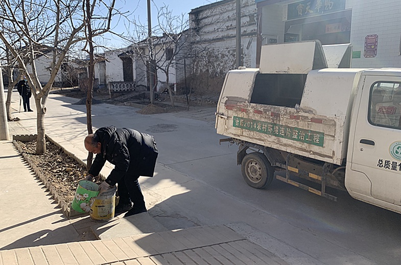 图为:范富生正在义务为家中无人的农户倒垃圾