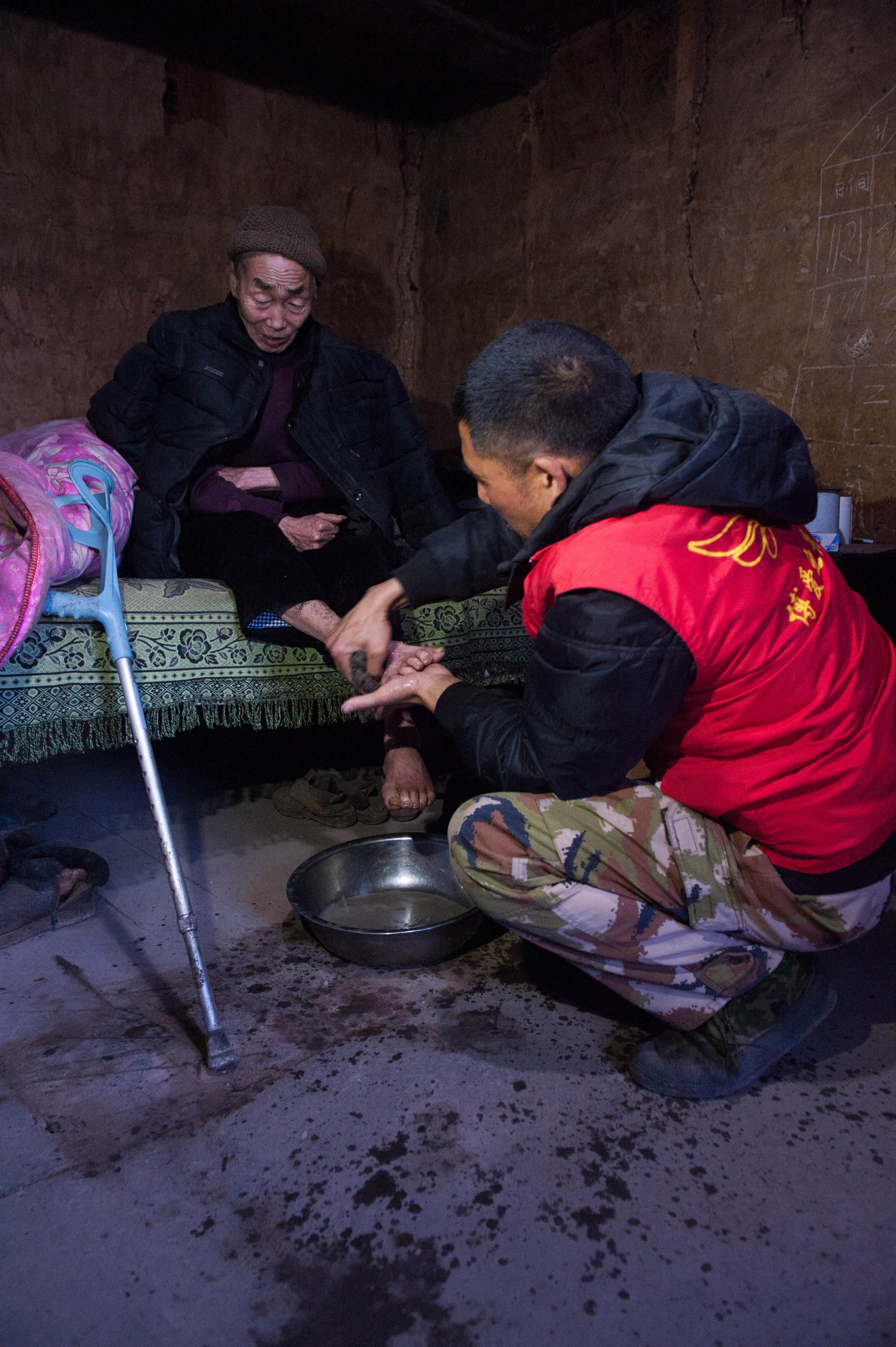 金果坪乡桃李溪村服务人员曹天周在给二级肢体残疾,71岁的老人谢坤柱