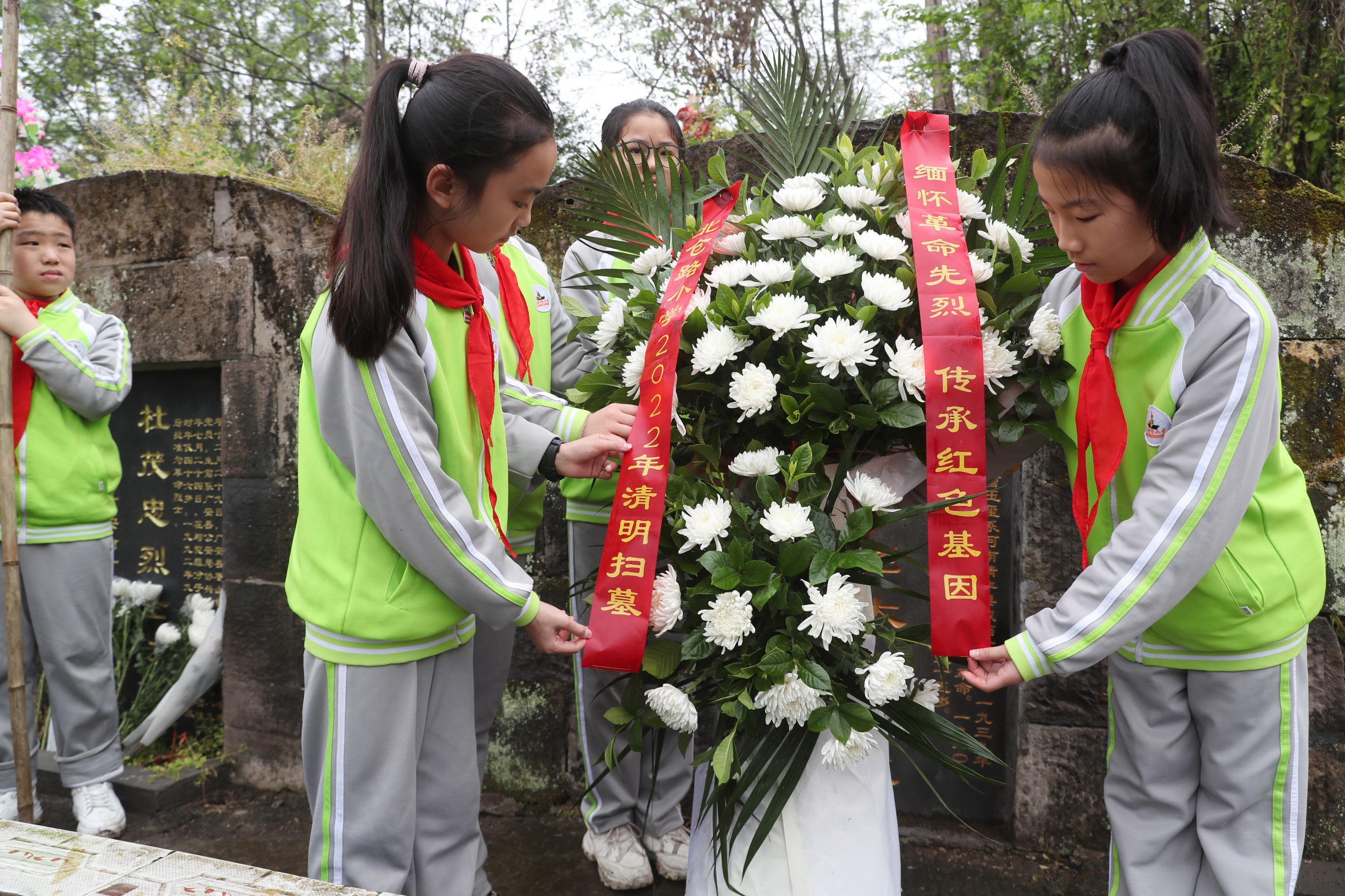 北仓路小学少先队员向烈士敬献花篮后整理缎带。