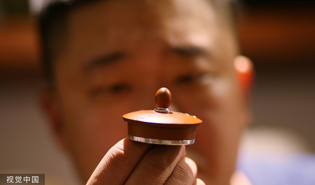 河南鄭州，鋦瓷藝人舉著完成的瓷器反復觀察?！颁|瓷”是我國一門古老的手藝，簡單來說就是把打碎的瓷器用銅、鐵、錫等金屬釘釘起來，使瓷器得以修復并再次使用。精細修復，容不得一點兒馬虎。東方/視覺中國