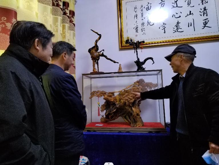 村民方启祥(右一)介绍自己的根雕作品 杨建东 摄