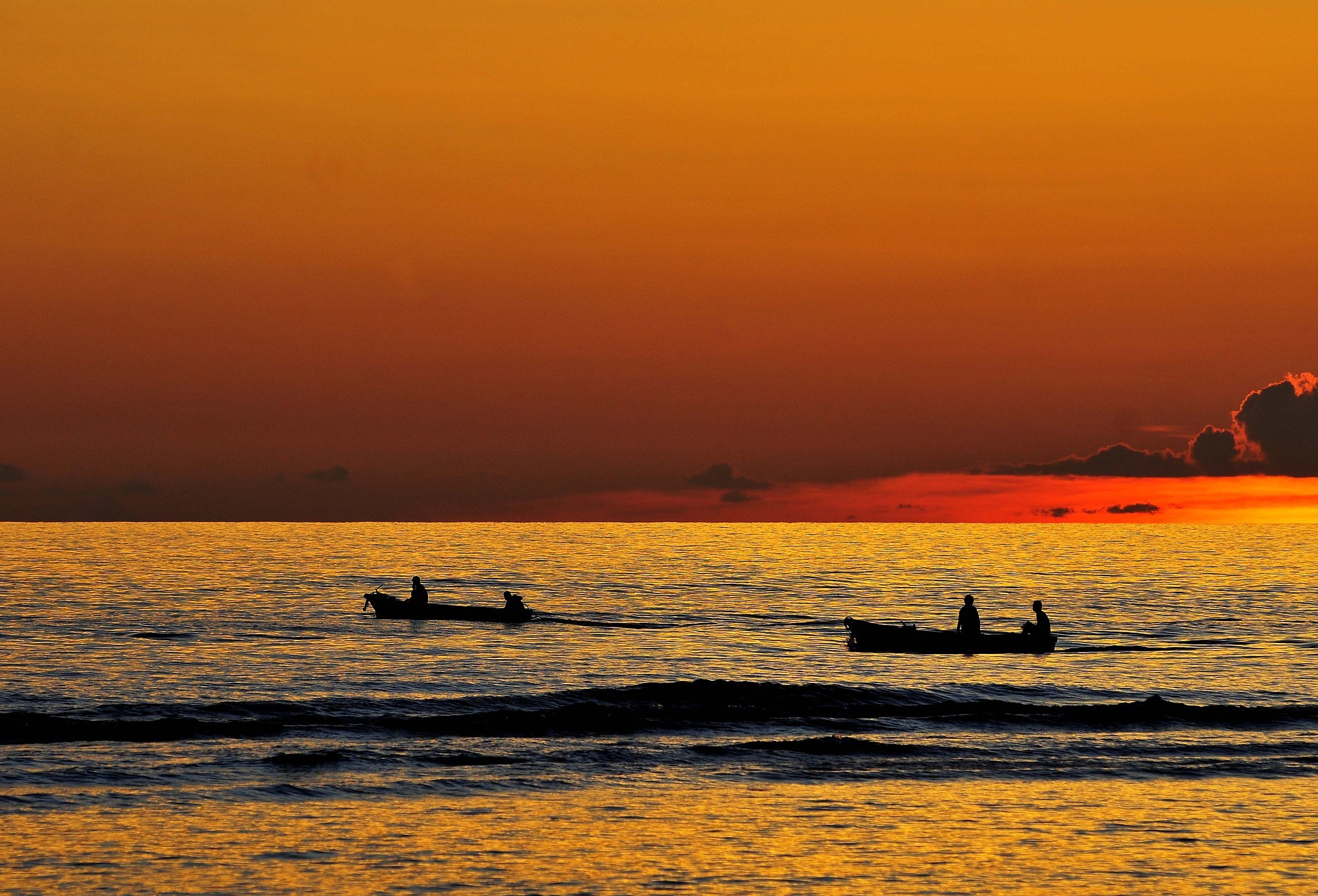 夕阳西下,红彤彤的霞光照在波光粼粼的海面上,渔船也开始返航.