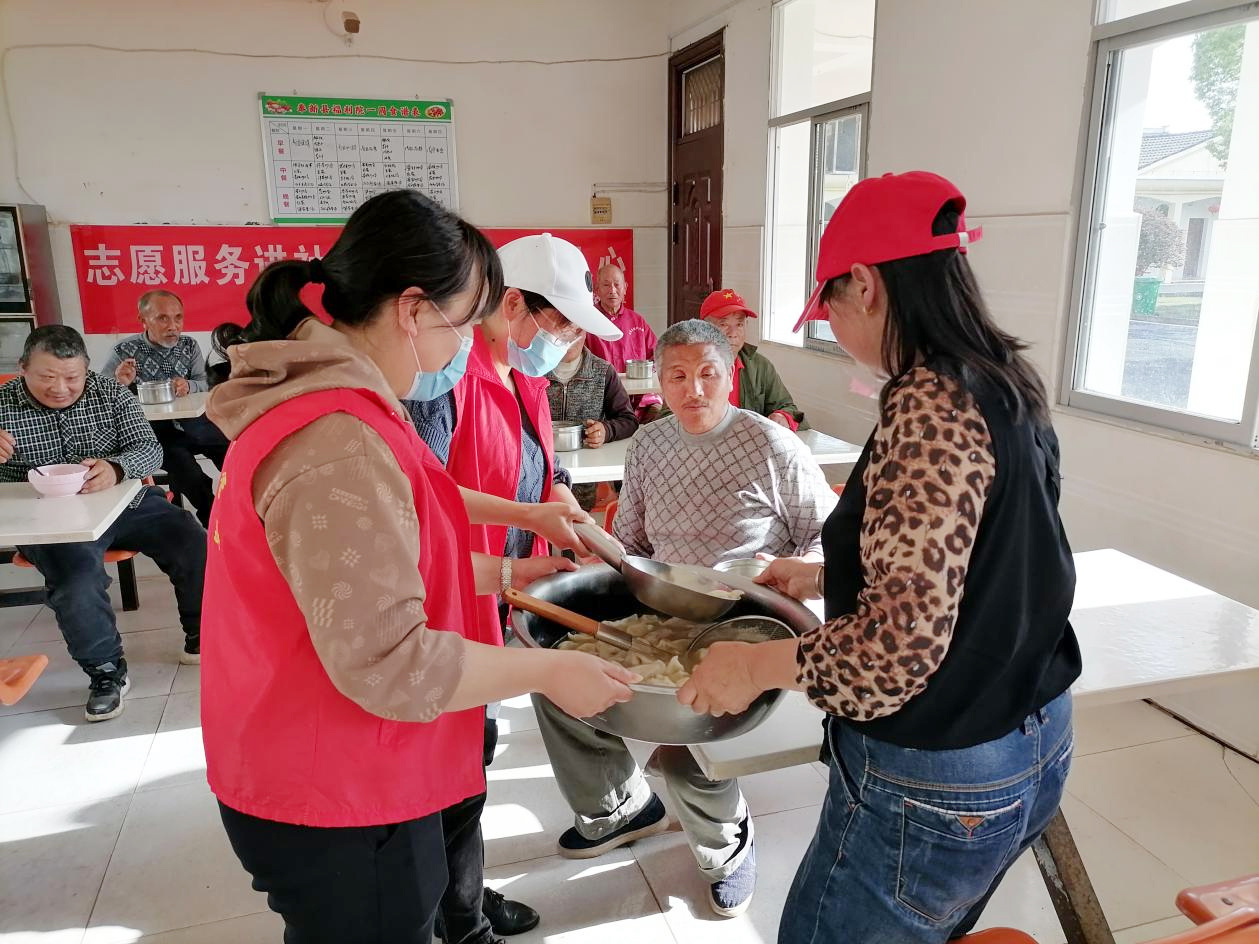 志愿者把煮熟的饺子端给老人品尝