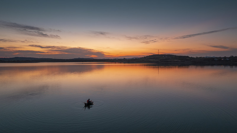 夕阳西下，晚霞映红湖面，一只小船行走在宁静的湖面上，给人留下了眷眷思念。